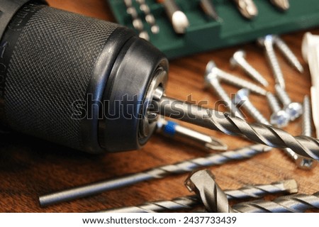 Close-up of a drill, set with drills and various materials on a wooden background. High quality photo