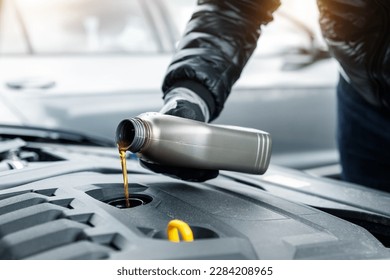 Close-up driver hand holding small bottle can pouring synthetic motor oil in diesel or petrol turbocharged vehicle engine due oil consumption. New lubricant diy change. Car service maintenance work - Powered by Shutterstock