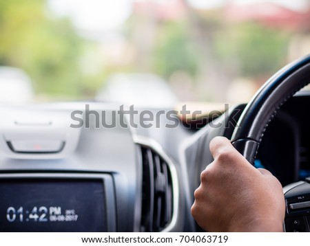 Closeup driver hands holding steering wheel while driving on the road.
