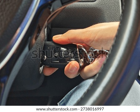 Close-up of a driver's hand inserting a key into a car's ignition