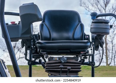 Closeup of driver's seat of asphalt compacting machine with the blurred sky and terrain in the background - Shutterstock ID 2254840919