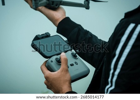 Closeup of drone pilot controlling flight in foggy hilltop environment in Kerala