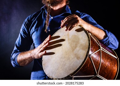Closeup drummer male hands with jembe. Man is drumming on wooden ethnic drum. Percussion musical instrument. Musician is playing live ethno rhytm music. Summer festival concept. Modern art hobby. 