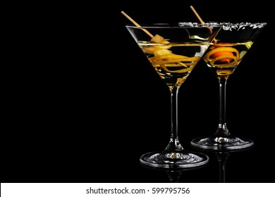 Close-up of dry martini with coconut rim, lemon peel and kumquat in the black background