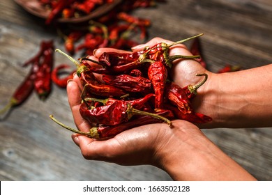 Closeup Dry Mexican Chilli Pepper In Hands Over A Wooden Table