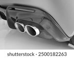 Close-up of a dual exhaust system on a sports car, captured in black and white. the modern design and sleek lines highlight the advanced automotive engineering and aesthetic detail