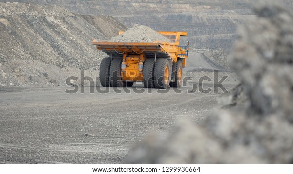 Close-up of dump truck moving on a quarry road\
loaded with ore. Back\
view.
