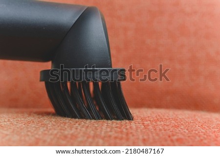 Closeup of a dusting brush nozzle attachment of a vacuum cleaner. Being used to clean the fabric surface of a couch.