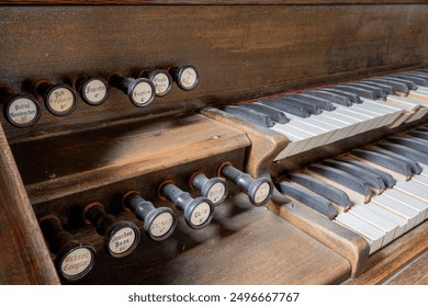Close-up of a dusty old organ with knobs labelled for different sound effects. Many of the keys are out of alignment.
