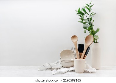 Closeup of eco-friendly kitchenware, utensils, towel and plant on table in kitchen with white walls. Home comfort. Household equipment. Earth-friendly products