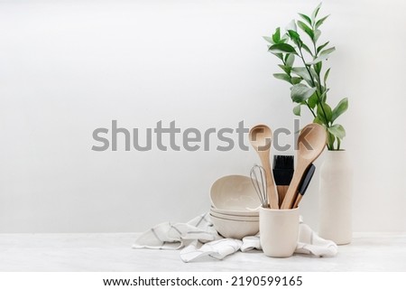 Closeup of eco-friendly kitchenware, utensils, towel and plant on table in kitchen with white walls. Home comfort. Household equipment. Earth-friendly products