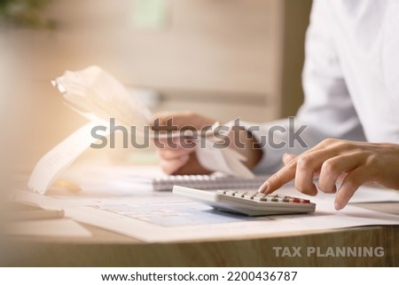 Close-up of economist using calculator while going through bills and taxes in the office.