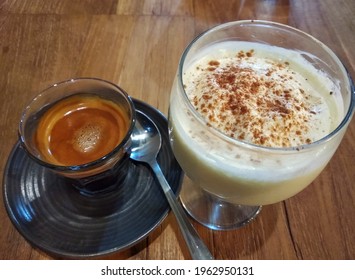 A closeup of eggnog next to a cup of fresh espresso