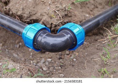 Close-up Of Elbow Fitting, Pvc Pipes At Bend In Dirt Trench Outdoors. Plumbing Water Drainage Installation. Underground Irrigation System
