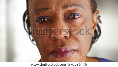 A close-up of a elderly black woman looking sad