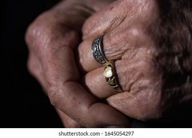 A closeup an elderly couple holding hands with a symbolic ring