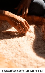 Close-up of elderly hands carefully sorting white rice in natural light. Traditional manual process with a cultural and rustic feel, symbolizing care, food, and labor.