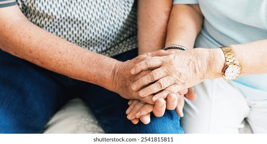 Close-up of elderly hands clasped together, symbolizing support and companionship. The image focuses on the warmth and connection between the individuals. Senior couple holding hands. - Powered by Shutterstock