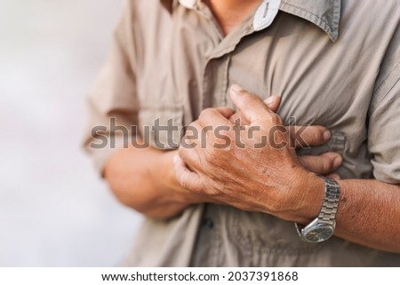 Close-up of an elderly man's hand held his chest in pain. Concept of heart disease.