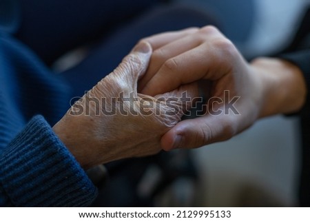 close-up of an elderly person's hand holding a young man's. Symbol of compassion and solidarity