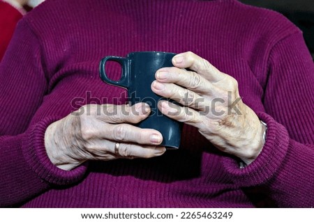 Close-up of an elderly woman holding a cup of hot coffee