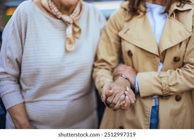 Close-up of an elderly woman holding hands with a younger companion, symbolizing support and companionship. The image conveys warmth, connection, and emotional support. - Powered by Shutterstock