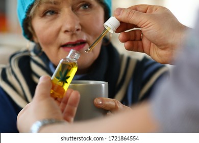 Close-up of elderly woman receives sedative drops from doctor. Glass bottle with leaf sign. Prescription herbal meds. Traditional medicine cannabinoid oil and healthcare concept