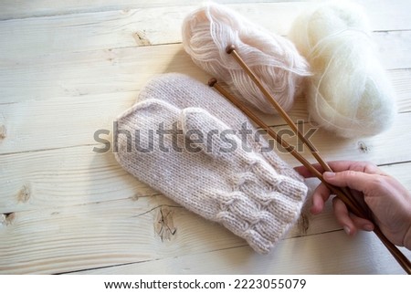 Close-up of an elderly woman's hand holding knitting needles. Wool knitted mittens