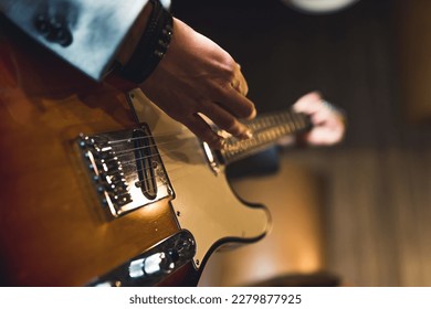 Closeup of electric guitar. Hands of unrecognizable caucasian person using electric guitar. Indoor shot. Blurred background. High quality photo