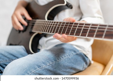 Closeup of electric guitar in hands of young boy in casual clothes - Powered by Shutterstock