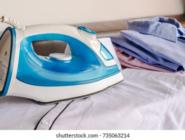 Closeup Electric Iron With Folding Cloth And Spray Starch On The Ironing Board.
