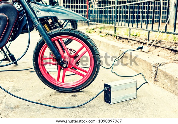 close-up\
of an electric motorcycle charging, e-bike, is charged with current\
and then inserted into the bike, green\
ecology,