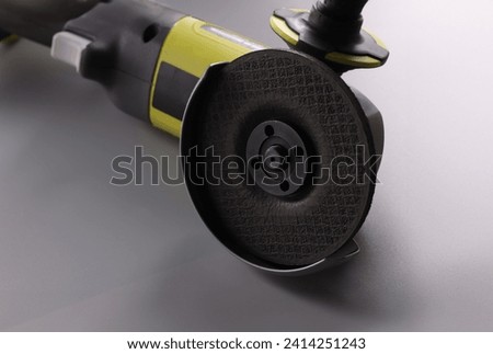 Close-up of electrical saw, grinder with nozzle on grey surface, detailed picture of powerful circular saw tool for construction works. Carpentry concept