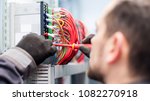 Closeup of electrician engineer works with electric cable wires of fuse switch box. Electrical equipment