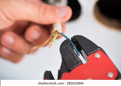 Closeup Of Electrician Hands Stripping Electrical Wires For Wall Socket