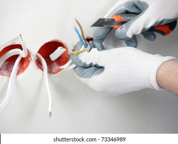 Closeup Of Electrician's Hands Stripping Electrical Wires For Wall Socket