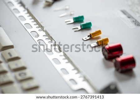 Close-up of electronic components including capacitors, connectors, and a metal strip, arranged on a white surface.