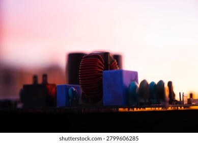 Close-up of electronic components on a circuit board against a vibrant sunset background.
