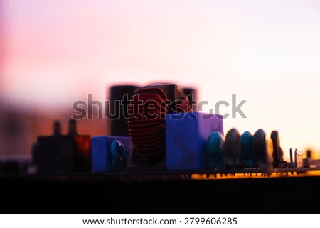 Close-up of electronic components on a circuit board against a vibrant sunset background.

