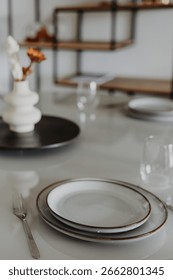 Close-up of elegant dining setting with ceramic plates and glass table in light-filled kitchen