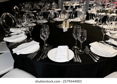 Close-up of an elegant round table setup, plates, glasses, and food dishes in a banquet hall