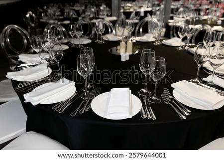 Close-up of an elegant round table setup, plates, glasses, and food dishes in a banquet hall