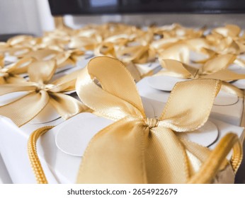 Close-up of elegant white gift boxes with golden ribbon bows, commonly used as wedding or event souvenirs