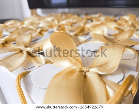 Close-up of elegant white gift boxes with golden ribbon bows, commonly used as wedding or event souvenirs