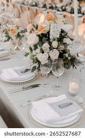 Close-up of an elegantly set wedding table with white linens, candles, and lush floral arrangements. A soft and romantic aesthetic for timeless wedding inspiration.