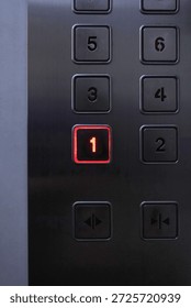 Close-up of an elevator control panel with the number 1 button glowing red, representing choice, decision making, priority, direction, and starting point. Concept of selection, destination, success, leadership, and first step.