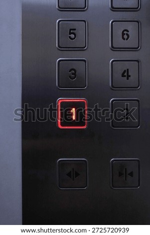 Close-up of an elevator control panel with the number 1 button glowing red, representing choice, decision making, priority, direction, and starting point. Concept of selection, destination, success, leadership, and first step.