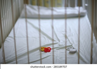 Closeup Of A Empty Baby's Crib With Left Toys