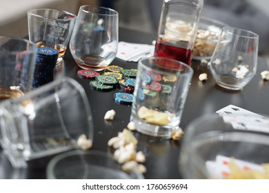 Close-up Of Empty Dirty Glasses, Poker Chips, Playing Cards And Popcorn On Table After Poker Party