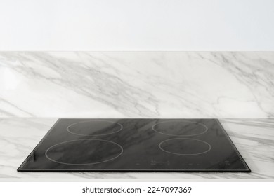 closeup of empty electrical glass ceramic hob with sensor buttons on control panel built in marble countertop and white wall background with copy space